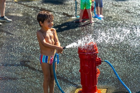 Happy child spraying water from a fire hydrant during a hot summer day in vancouver, british