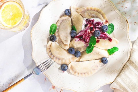 Handmade dumplings filled with sweet ingredients, arranged beautifully on a white plate, topped