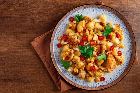 Spicy fried cauliflower served on a wooden countertop