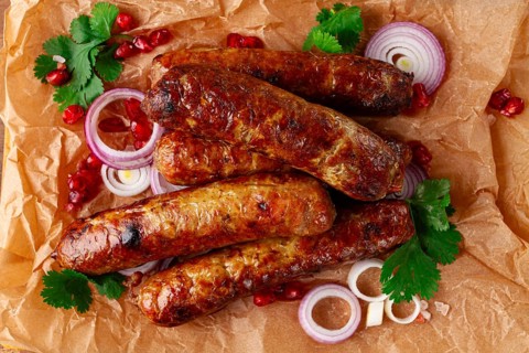 Fried kupaty on parchment, with red onion and pomegranate, kupaty, Georgian cuisine