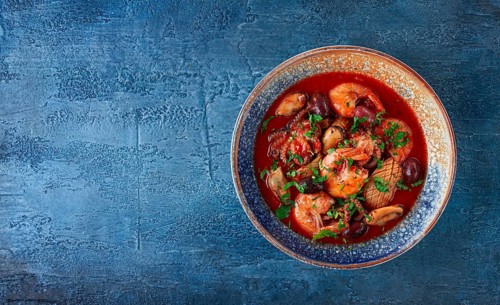 Seafood in tomato sauce with olives, on a dark blue background
