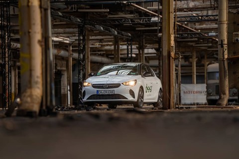 A white car with car sharing logo is parked in an old industrial building, Deer E-Car Sharing,