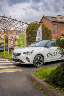 Opel with car sharing logo stands in front of an advertising banner in an urban setting with