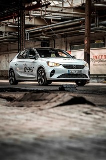 A small car against an industrial backdrop with structured elements and rugged charm, Deer E-Car