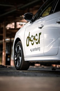 Side view of a white car sharing vehicle in an industrial environment, Deer E-Car Sharing,