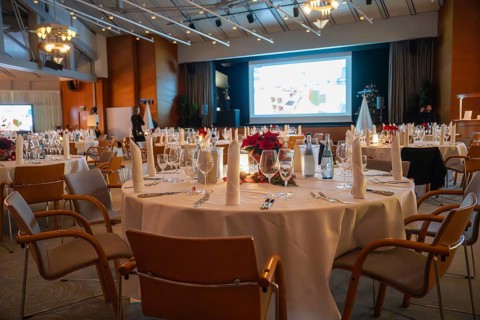 A tastefully furnished room with set tables and a large screen, Christmas party Dekra Congresshotel