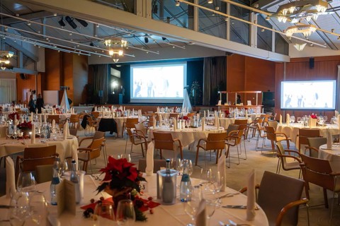 An elegant event room with set round tables and festive lighting, Christmas party Dekra