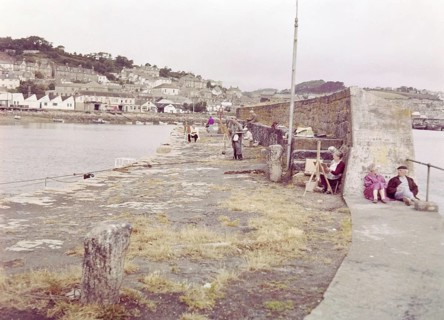 Artists painting on the sea wall in the harbour pf fishing village, Newlyn, Cornwall, England, UK c