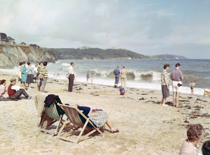 People on sandy beach looking at breaking waves, Gyllyngase beach, Falmouth, Cornwall, England, UK