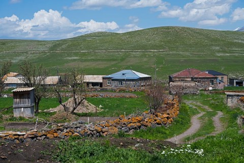 Quiet rural village with stone houses and green fields under blue sky, Jigrasheni,