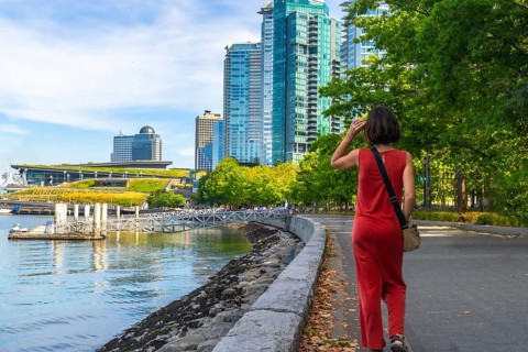 Tourist walking along the scenic seawall in vancouver, enjoying the sunny summer day while