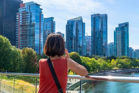 Tourist is making a phone call while enjoying the view of the modern buildings of vancouver's