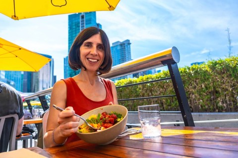 Happy woman enjoying a healthy poke bowl at an outdoor restaurant patio in vancouver, british