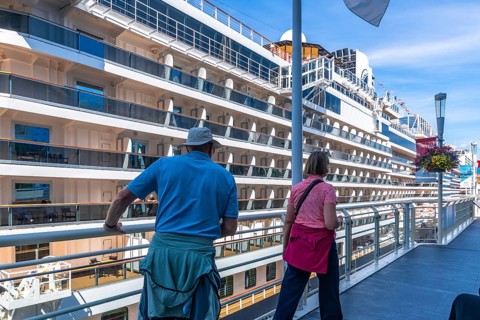 Two tourists are enjoying the view of a large cruise ship docked at canada place in vancouver,