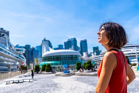 Happy tourist admiring the stunning vancouver downtown skyline, featuring cruise ships docked at