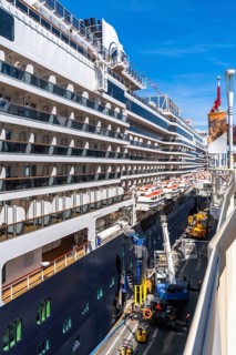 Large cruise ship docking in vancouver, british columbia, with lifeboats hanging from the side and