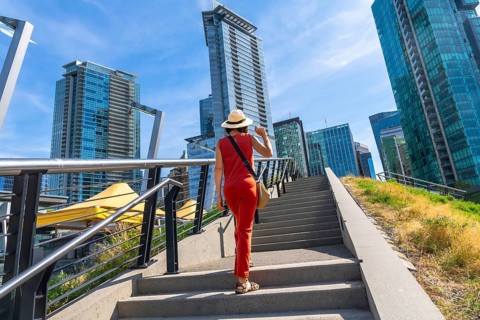Female tourist wearing a straw hat and red jumpsuit walking up stairs in downtown vancouver,
