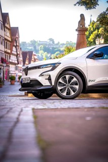 Profile view of a white car in a picturesque historic town in sunshine, Deer e-car sharing, Renault