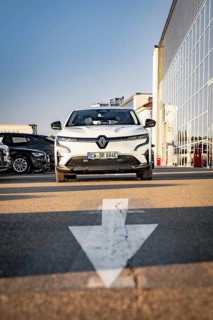 A modern white car is parked in a parking lot in front of a glass front, Deer E-Carsharing, Renault