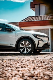 White electric car standing on paved ground in front of a modern house, Deer e-Carsharing, Renault