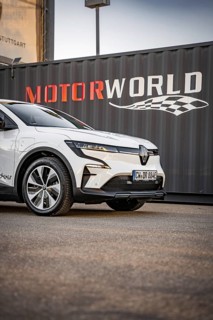 Close-up of a white electric car in front of a container with Motorworld logo, Deer E-Carsharing,