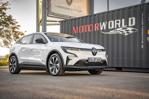 A white electric car stands in front of a Motorworld container on a concrete surface, Deer