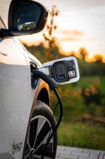 A white electric car is charged by a charging cable at sunset, Deer E-Carsharing, Renault Megane,