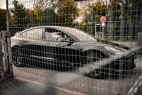 Black car parked at a fence grid in an urban area, Deer E-Carsharing, Tesla Model 3, Calw, Germany