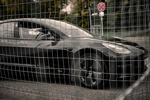 Black car behind a metal grid in an urban environment, Deer e-Carsharing, Tesla Model 3, Calw,