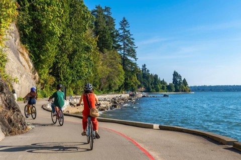 Tourists are cycling on the seawall in stanley park, enjoying the scenic views of the ocean and