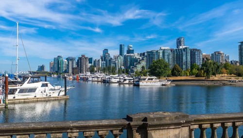 Luxury yachts and sailboats are moored in coal harbour marina, with the modern skyline of