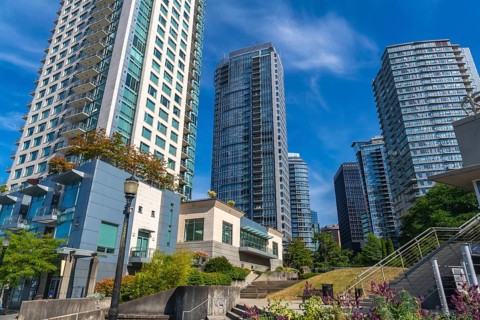 Modern skyscrapers rise above a green park in vancouver, british columbia, creating a vibrant urban