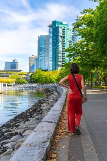 Tourist walking on the seawall in vancouver downtown with modern buildings and green trees in the