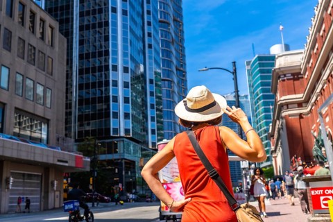 Female tourist wearing a straw hat and an orange dress is admiring the skyline of vancouver,