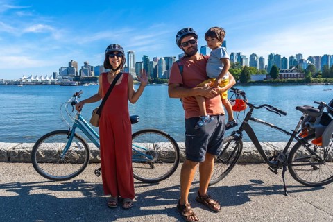 Happy family with bicycles enjoying a sunny day by the sea, taking a break from their ride with the