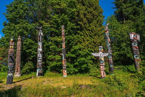 Totem poles representing indigenous art are standing in a park in vancouver, british columbia,