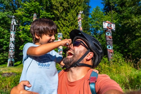Playful father and son are enjoying a sunny day at brockton point in stanley park, vancouver,