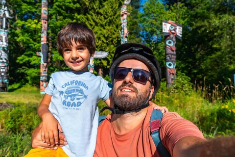 Father and son enjoying a sunny day at brockton point in stanley park, vancouver, taking a selfie