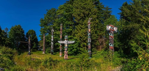 Totem poles rising against a backdrop of lush greenery and blue sky, reflecting the rich history