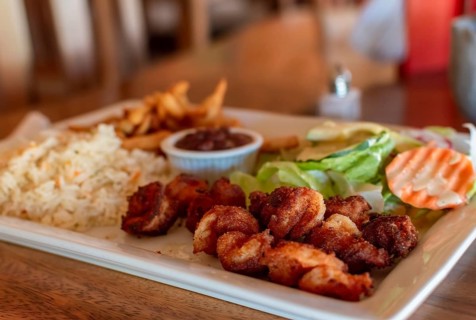 Breaded shrimp with rice and salad served on wooden table. Close up of breaded shrimp with french