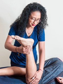 Physiotherapist performing knee flexion physiotherapy, Physiotherapist with patient performing knee