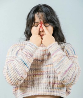 Close up of young woman with sinus pain touching nose isolated. Asian woman with rhinitis touching