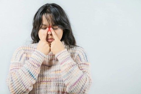 Asian woman with rhinitis touching nose. Close up of young woman with sinus pain touching nose