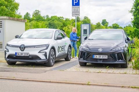Two electric cars are parked at the outdoor charging station with a woman nearby, Deer E-