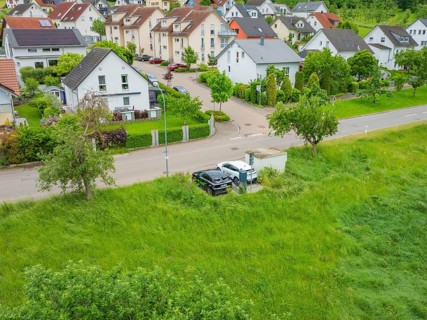 Aerial view of a suburb with houses and a street surrounded by greenery, Deer E-Carsharing, Calw,