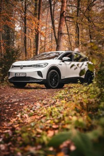 White car in autumn forest on a dirt road, Deer E-Carsharing, VW ID4, Calw, Germany