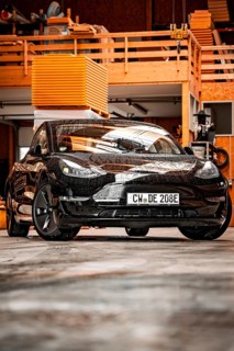 Black Tesla in a workshop environment with industrial flair, Deer e-Carsharing, Tesla Model 3,