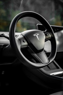 Close-up of a black steering wheel in a modern vehicle interior, Deer e-Carsharing, Tesla Model 3,