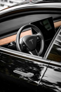 Black steering wheel with wood decor in modern car interior, side perspective, Deer e-car sharing,