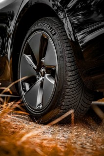 Close-up of a black car tire on a gravel path with grass in the foreground, Deer e-car sharing,